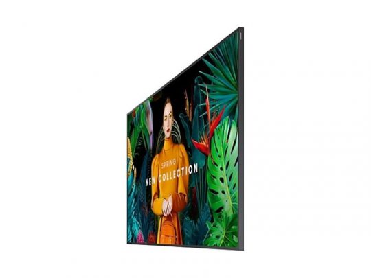 Samsung QB85C 85-Inch Smart Signage Display for rent, side view, showing a vivid advertisement with a woman in an orange outfit surrounded by green tropical plants and the text SPRING NEW COLLECTION onscreen. Ideal for digital signage and promotional displays.