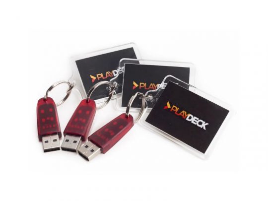 Drei rote PLAYDECK Lite Dongles mit silbernem Schlüsselring und einer schwarzen Karte mit PLAYDECK-Logo liegen nebeneinander auf weißem Hintergrund. Die PLAYDECK Lite Dongles dienen als Lizenzschlüssel für die professionelle Playout-Software, die flexibel gemietet oder gekauft werden kann.